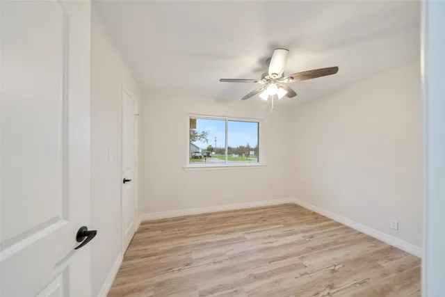 a view of a room with wooden floor and a ceiling fan