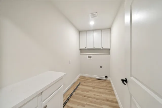 a view of a kitchen with white cabinets and wooden floor