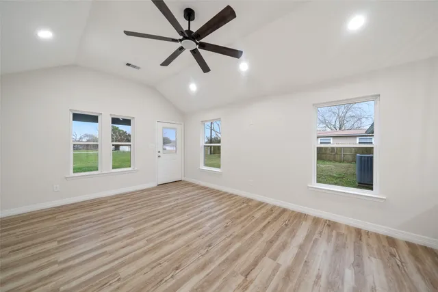 a view of an empty room with a window and wooden floor