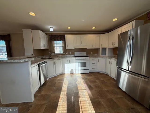 a kitchen with granite countertop stainless steel appliances refrigerator sink microwave and cabinets