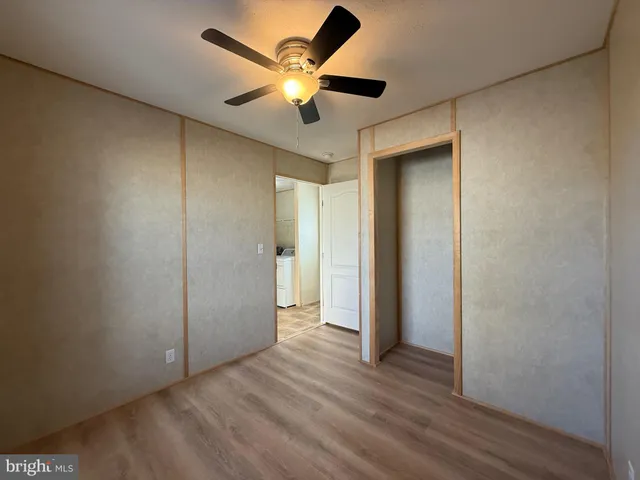 an empty room with wooden floor and a ceiling fan