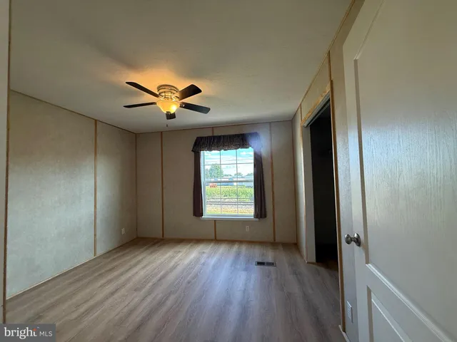 a view of empty room with wooden floor and ceiling fan
