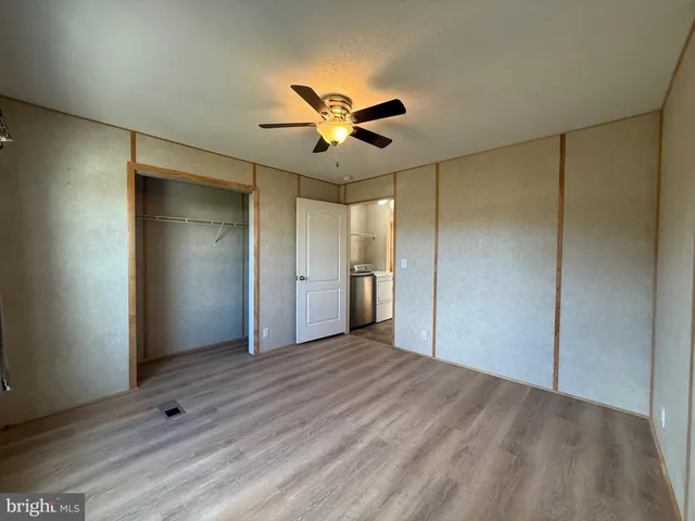 a view of empty room with wooden floor and fan