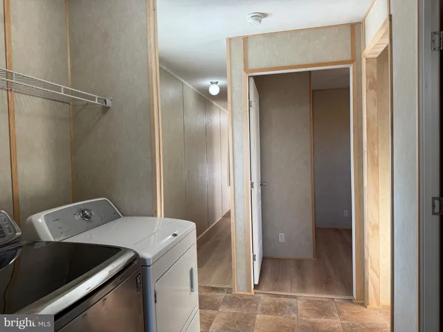 a large kitchen with granite countertop a stove a sink dishwasher and a microwave oven with white cabinets