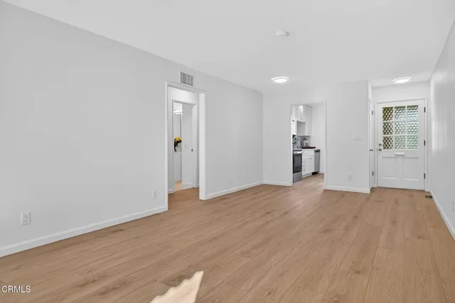 a view of empty room with wooden floor and window