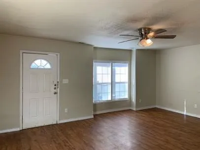 an empty room with wooden floor chandelier fan and windows