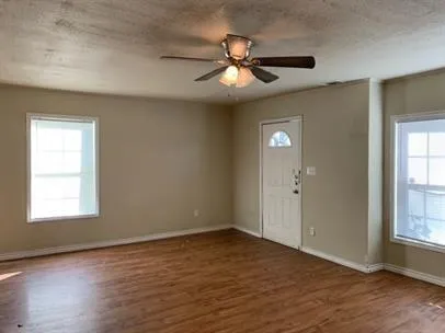a view of an empty room with wooden floor and a window