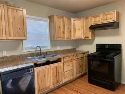 a kitchen with granite countertop a stove sink and cabinets