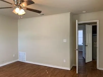 an empty room with wooden floor closet and windows
