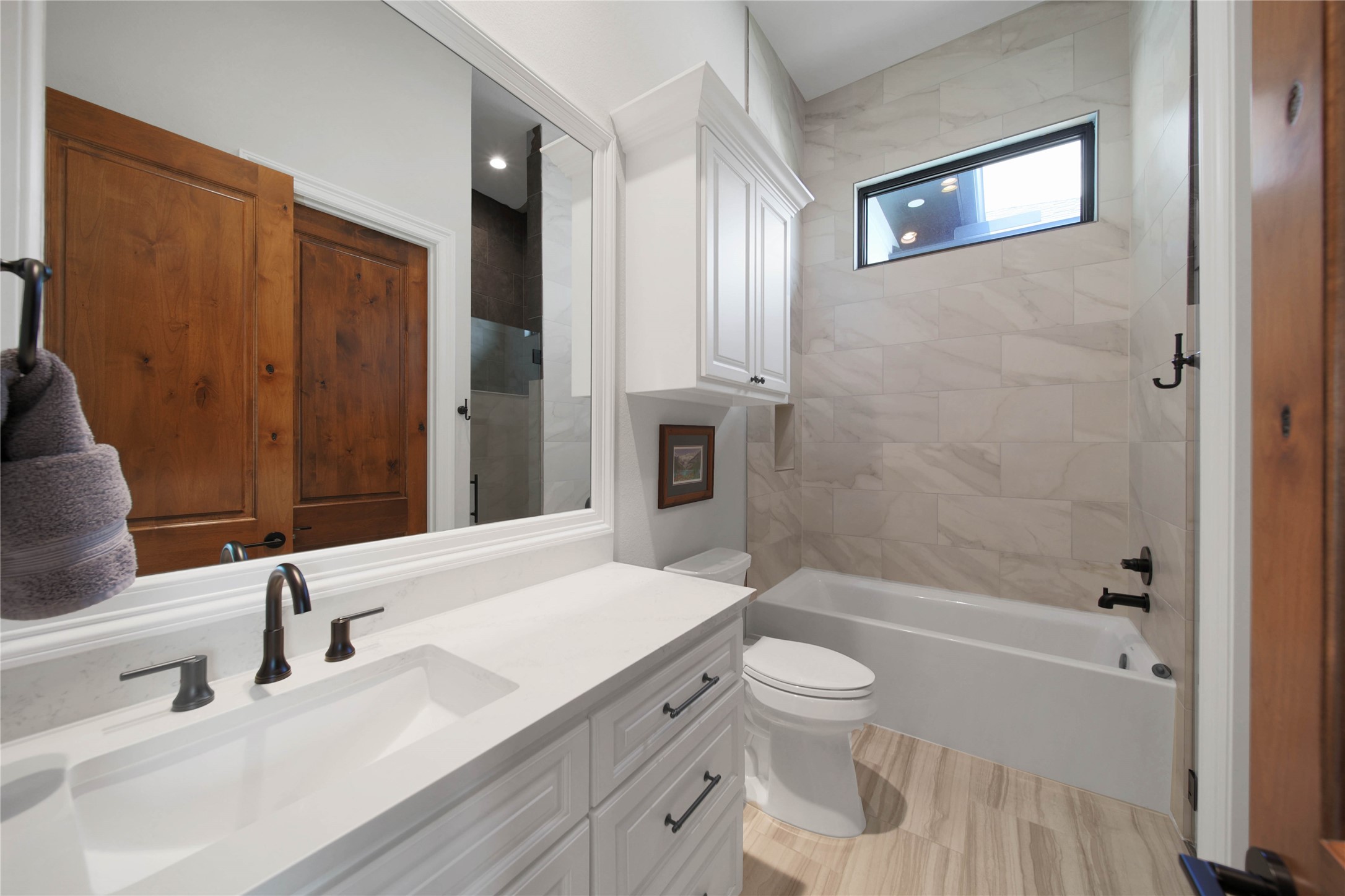 24718 Shadow Pond Spring, TX 77389 - Photo 30 of 49 Elegant bathroom featuring a sleek double vanity with modern fixtures, a spacious tub with tiled surround, and warm wooden accents for a cozy touch.
