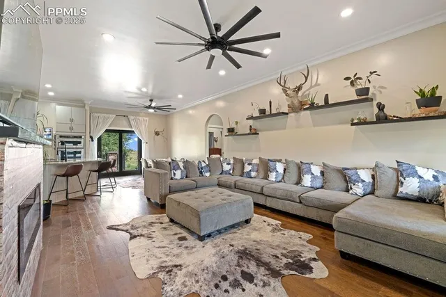 a living room with furniture kitchen view and a wooden floor