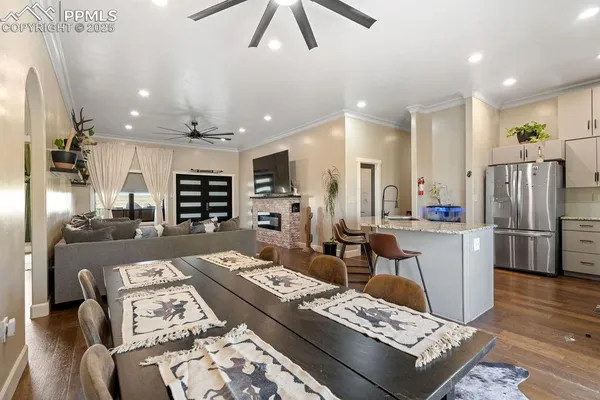 a kitchen with stainless steel appliances kitchen island granite countertop a dining table chairs and a refrigerator