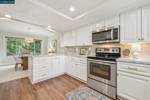 a kitchen with stainless steel appliances white cabinets a stove a sink and a microwave