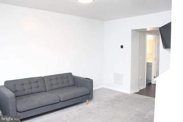 a living room with furniture and a walk in closet with wooden floor