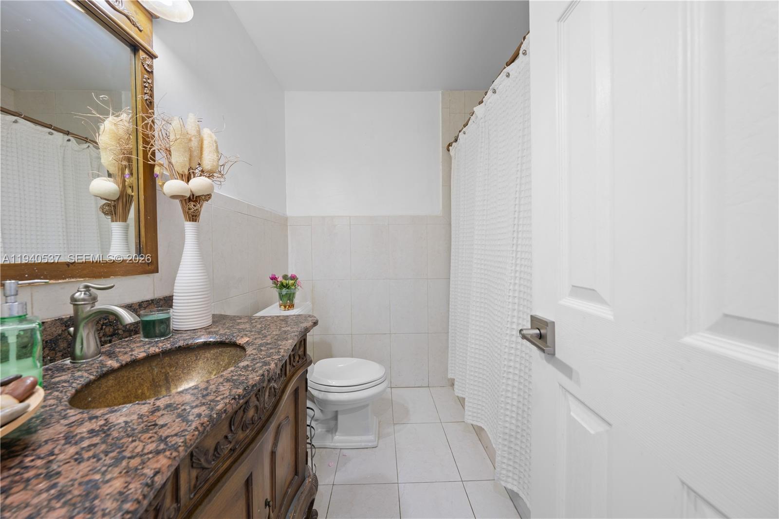 6423 Southwest 107th Place Miami, FL 33173 - Photo 26 of 37 a bathroom with a granite countertop sink a toilet and a mirror