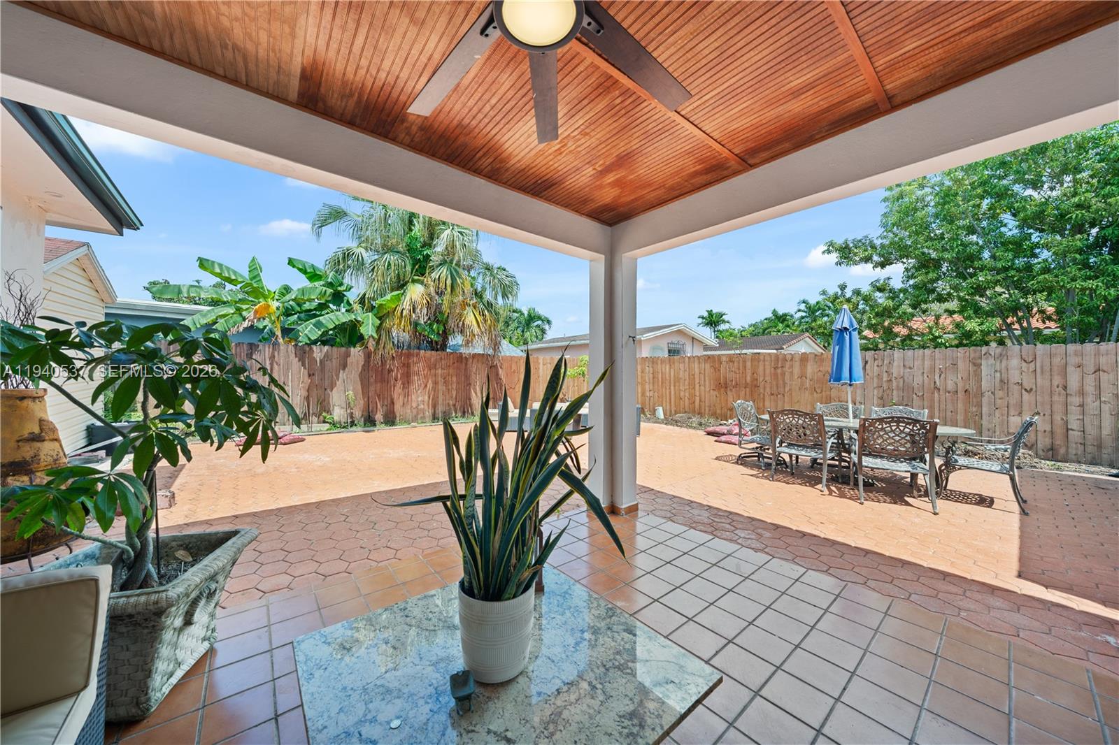 6423 Southwest 107th Place Miami, FL 33173 - Photo 30 of 37 a view of a patio with table and chairs potted plants with wooden fence