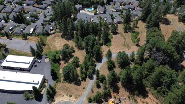an aerial view of residential houses with outdoor space and trees all around
