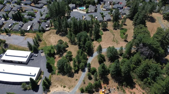 an aerial view of residential houses with outdoor space and trees all around