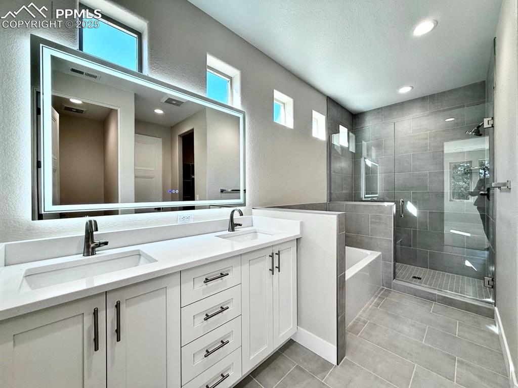 3135 Promise Point Colorado Springs, CO 80921 - Photo 22 of 33 Full bath featuring double vanity, a stall shower, a garden tub, recessed lighting, and a textured wall