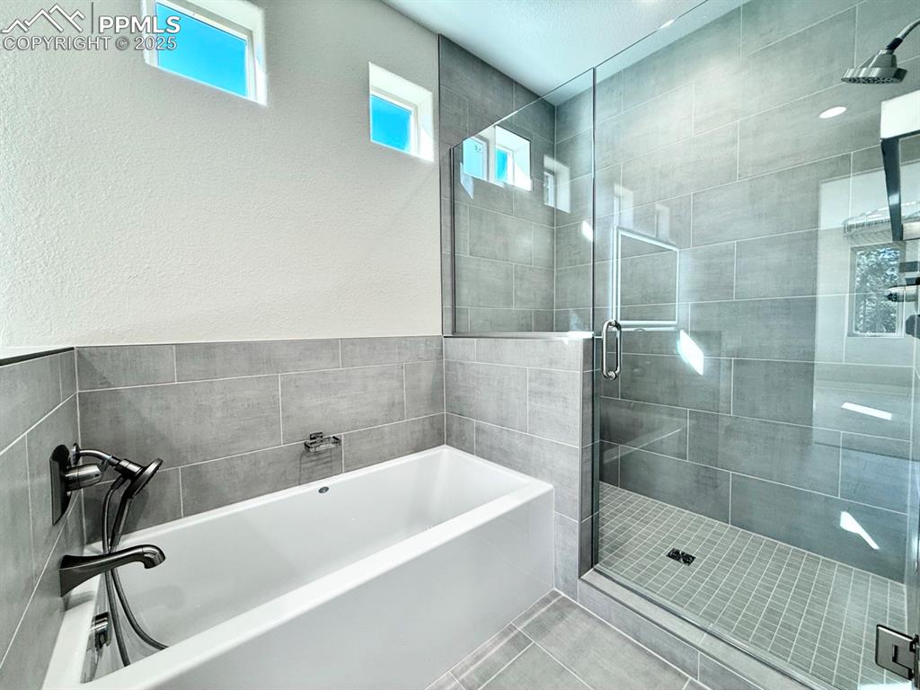 3135 Promise Point Colorado Springs, CO 80921 - Photo 24 of 33 Full bath featuring a garden tub, a shower stall, tile patterned floors, and a textured wall