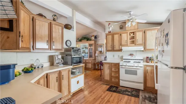 a kitchen with stainless steel appliances granite countertop a stove a sink dishwasher and white cabinets with wooden floor