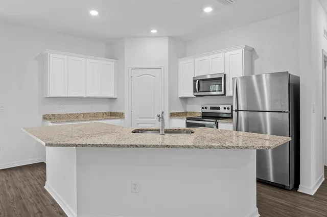 a kitchen with stainless steel appliances granite countertop a refrigerator a stove a sink and a microwave