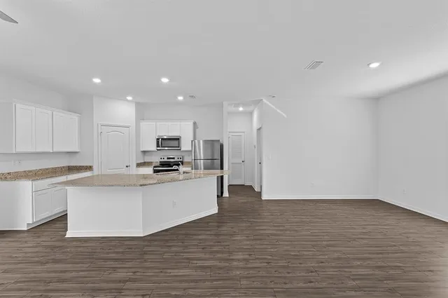 a kitchen with stainless steel appliances granite countertop a stove top oven a sink and white cabinets