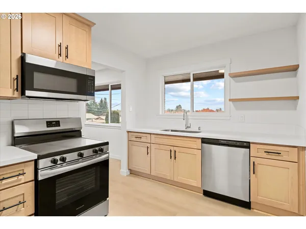 a kitchen with stainless steel appliances a sink cabinets and a window