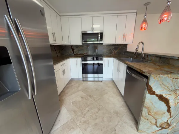 a kitchen with stainless steel appliances granite countertop a refrigerator a stove a sink and a microwave