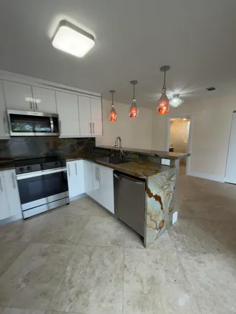 a kitchen with granite countertop a sink cabinets and stainless steel appliances