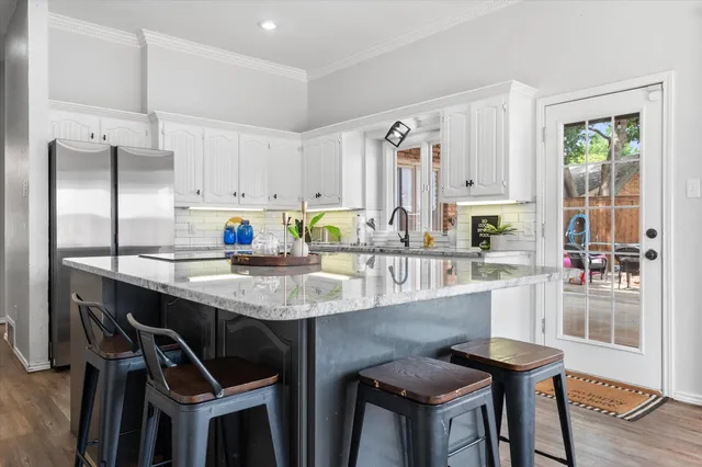 a kitchen with granite countertop a table chairs stove and refrigerator