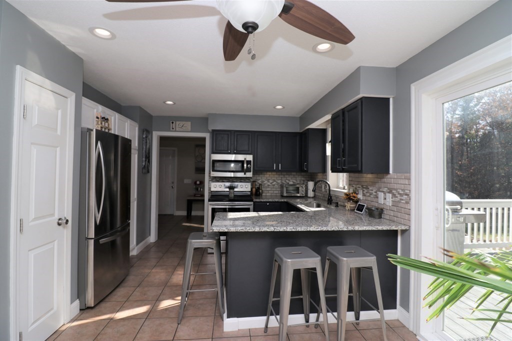 389 County Road Ashby, MA 01431 - Photo 8 of 34 a kitchen with stainless steel appliances kitchen island granite countertop a refrigerator a sink a stove a dining table and chairs with wooden floor