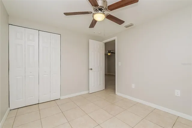 an empty room with closet and a chandelier fan