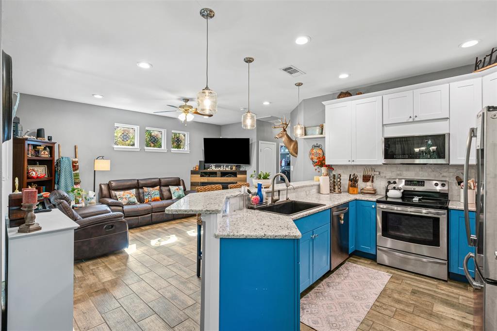 905 Poe Street Azle, TX 76020 - Photo 15 of 30 a large kitchen with kitchen island granite countertop a sink counter top space appliances and cabinets
