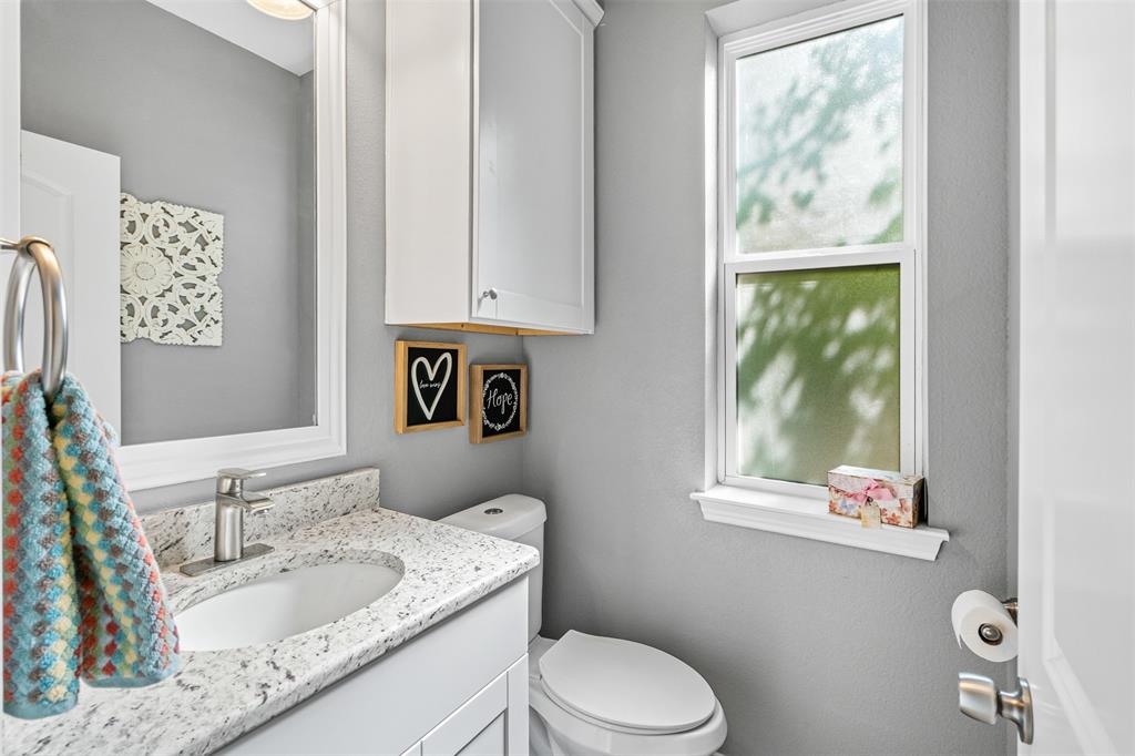 905 Poe Street Azle, TX 76020 - Photo 10 of 30 a bathroom with a granite countertop sink a mirror and a toilet
