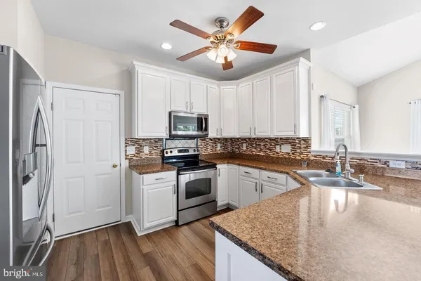 a kitchen with kitchen island granite countertop a sink appliances cabinets and counter space