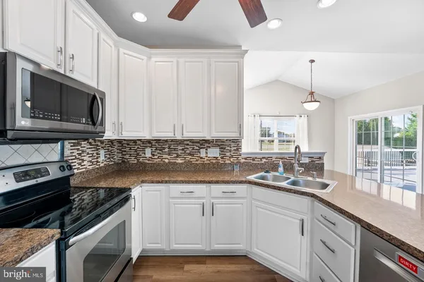 a kitchen with granite countertop cabinets stainless steel appliances and wooden floor