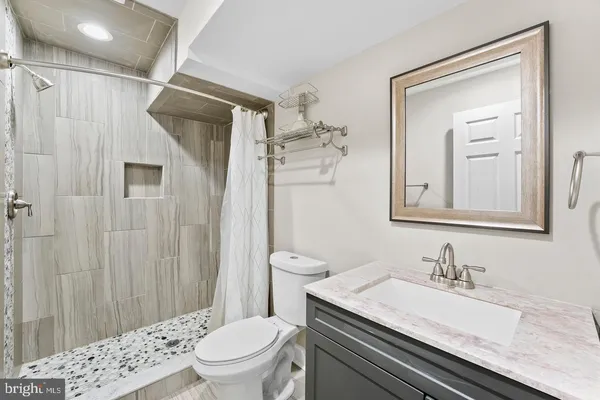 a bathroom with a granite countertop sink a toilet and shower