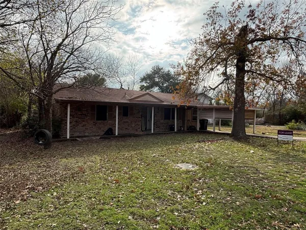 a view of a house with a yard and large tree