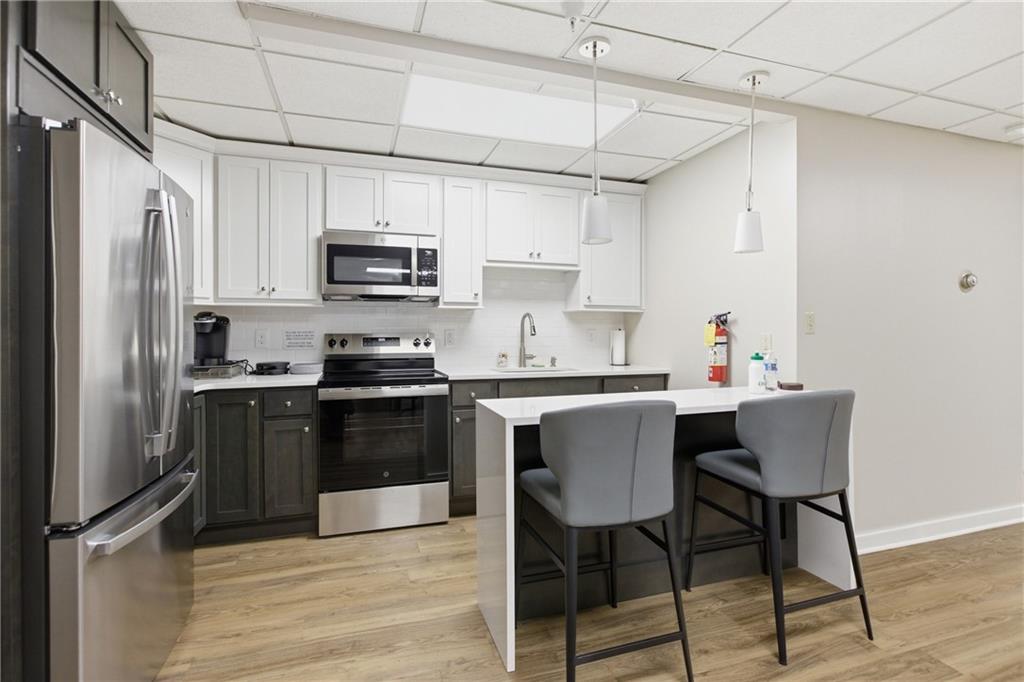 750 Washington Road, Unit 307 Pittsburgh, PA 15228 - Photo 19 of 24 a kitchen with stainless steel appliances a stove a sink refrigerator and a refrigerator with wooden floor