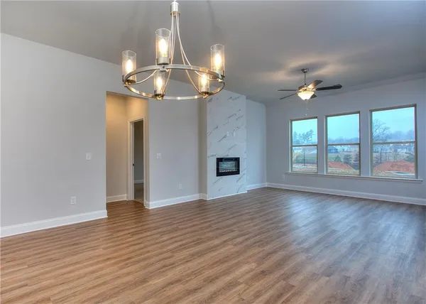 a view of an empty room with wooden floor fireplace and a window