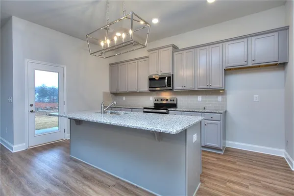 a kitchen with kitchen island granite countertop a sink cabinets and stainless steel appliances