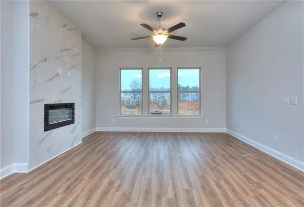 an empty room with wooden floor chandelier fan and windows