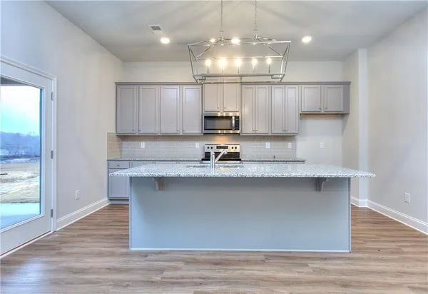 a kitchen with kitchen island granite countertop a sink cabinets and wooden floor