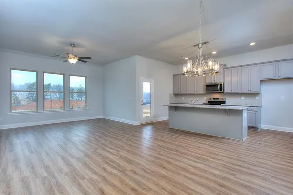 a view of kitchen with granite countertop stainless steel appliances sink cabinets and wooden floor