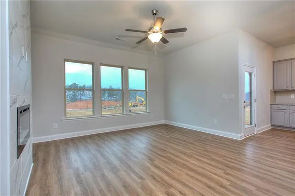 an empty room with wooden floor chandelier fan and windows