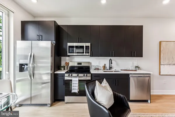 a kitchen with stainless steel appliances a sink a stove a refrigerator and cabinets