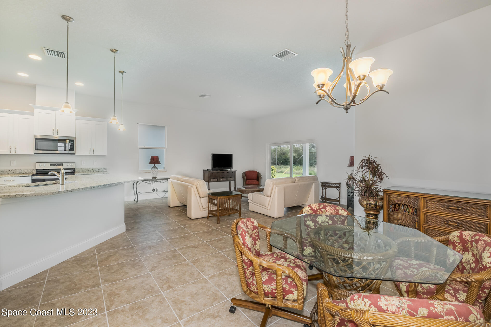 665 Lorelei Avenue Melbourne, FL 32901 - Photo 19 of 32 a kitchen with kitchen island stainless steel appliances a table chairs in it and wooden floor
