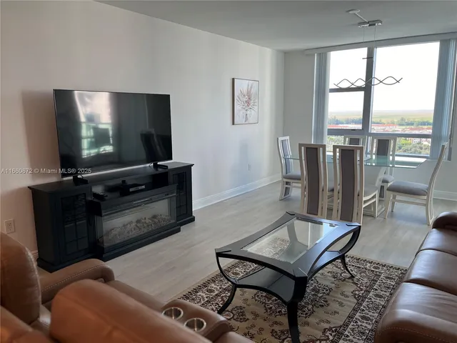 a living room with furniture a flat screen tv and a floor to ceiling window