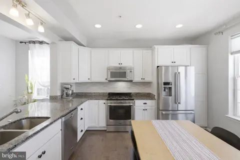 a kitchen with kitchen island granite countertop a stove sink and refrigerator